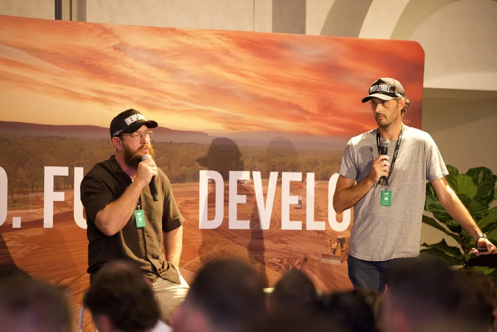 Two coaches presenting on stage in front of the Find. Fund. Develop. screen