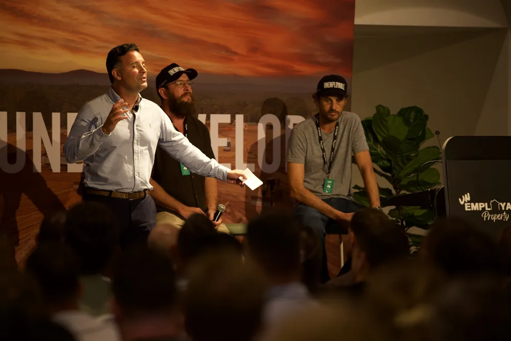 Three presenters taking questions at the front of the room